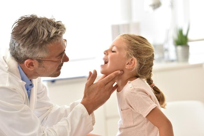 רופא בודק ילדה כדי לאבחן את מחלת השקד השלישי
