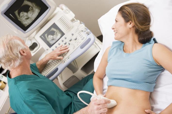 רופא מבצע סקירת מערכות לאישה צעירה במהלך ההריון