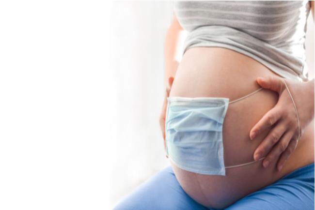 אישה בהריון בתקופת הקורונה שמה מסכה על הבטן כדי להגן על העובר שלה