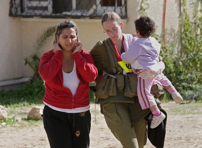 חיילת עוזרת בפינוי של אם וילד בזמן מלחמה. מלחמה ודיכאון בישראל
