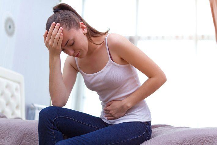 אישה יושבת ומחזיקה את הבטן בזמן PMS