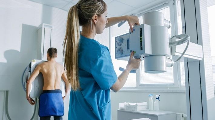 טכנאית רנטגן מצבעת צילום רנטגן בבחור של צילום חזה בבחור שעומד ללא חולצה