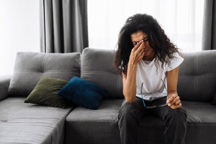 אישה בחרדה יושבת על ספה, טיפול בחרדה ודיכאון